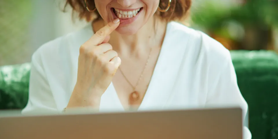 woman on computer pointing to teeth