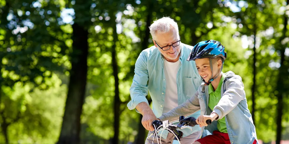 grandpa helping grandson ride bike outdoors