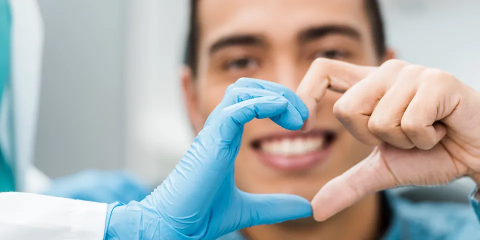 dentist and patient making a heart with hands